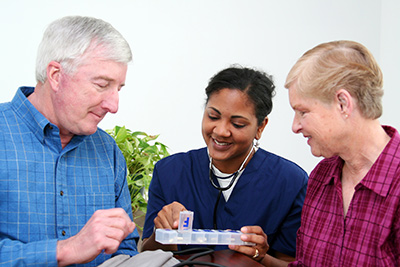 Nurse with two patients opening a pill dispenser